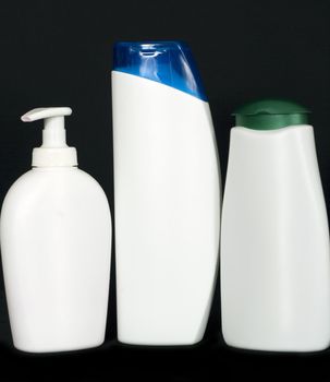 Three white plastic bottles arranged in a row on black background
