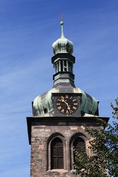 Closeup of old belfry with clock against blue sky