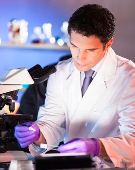 Health care professional looking at the microscope slide in the forensic laboratory.