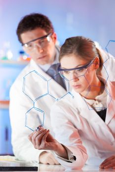 Portrait of a focused health care professionals in their working environment writing structural chemical formula on a glass board.