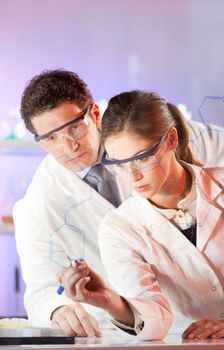 Portrait of a focused health care professionals in their working environment writing structural chemical formula on a glass board.