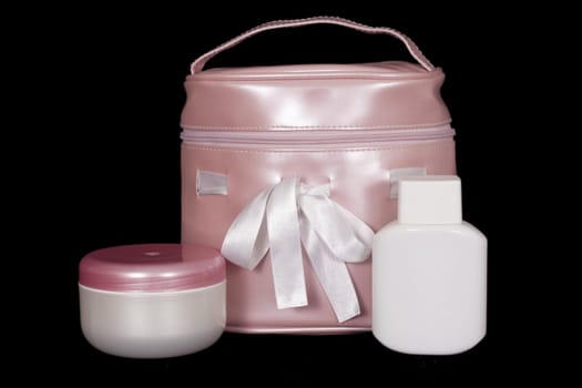 Pink bag for cosmetics, and two cans of cream on a black background
