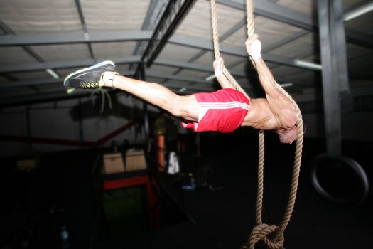Crossfit rope climb training on a dark background.
