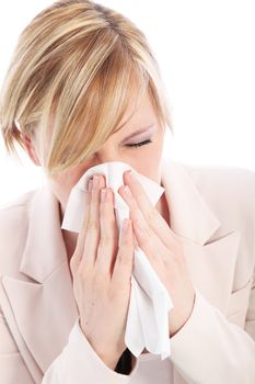 Young blonde woman is suffering from a cold or flu and is sneezing into a tissue. Studio portrait over white