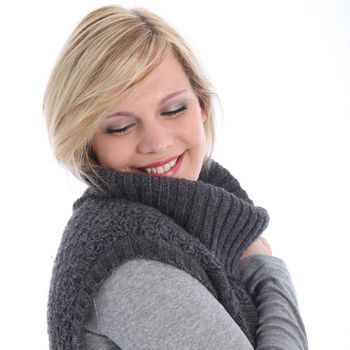 Beautiful young blonde woman smiling in bliss as she snuggles down into the warmth of her poloneck jersey on a cold winter day isolated on white