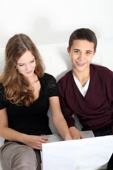 High angle view of an attractive young teenaged brother and sister sitting on a couch surfing the web on a laptop
