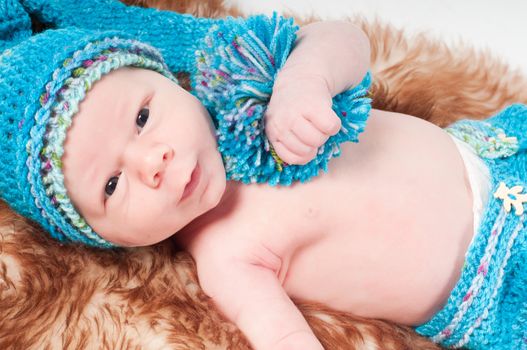 Newborn baby in long blue knitted hat with pom-pon