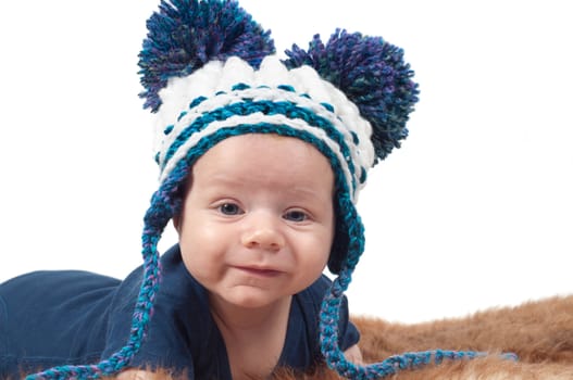 Cute baby in knitted hat with big pom-pons watching on you