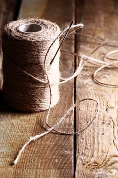 Artistic image of spool of thread and needle over wooden surface