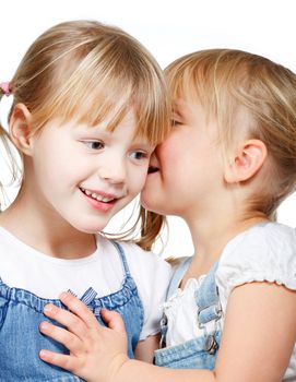 Portrait of little girl telling a secret to her friend over a white background