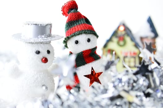 two snowmen in front of a house in artificial snow on white background