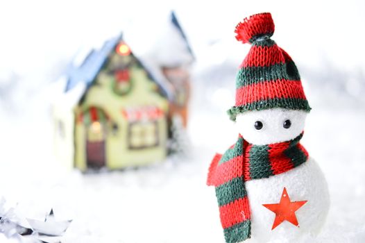 snowman with black and red hat and scarf in artificial snow on white background