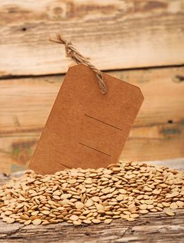 Lentil seeds with blank price tag on a wooden background