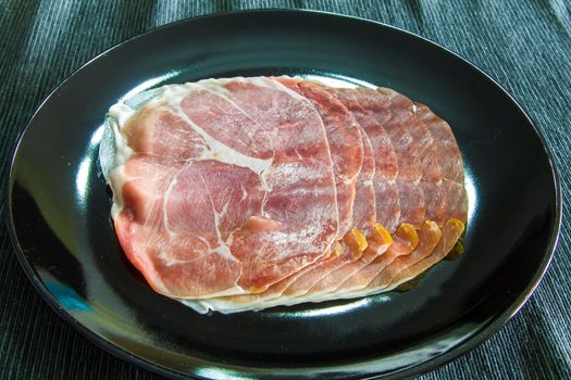 Raw ham on a black serving plate