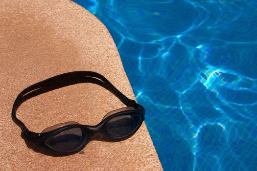 Dive goggles at the border of a swimming pool