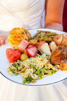 The meal of a bride on her wedding day looks healthy and cooked well with potatoes, fruit, pasta salad, green beans, chicken and more.