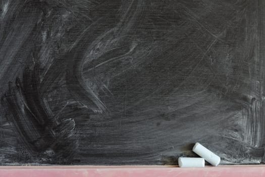 detailed black chalkboard fragment with two chalk pieces