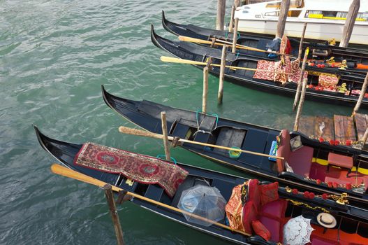 Four Venetian Gondolas, docked waiting for tourists near the Rialto Bridge on Grand canal in Venice, Italy.