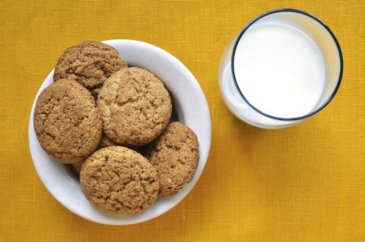 white plate with oat cookies and glass with milk