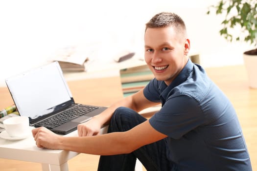 Young and happy guy with laptop relaxing at home