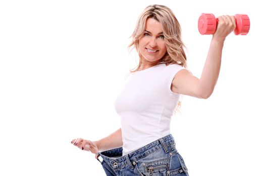 Happy mid aged woman in big pants after weight losing with dumbbell in hand