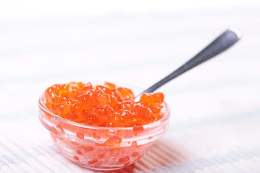 Close up of red tasty caviar in a glass jar with spoon