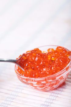 Close up of red tasty caviar in a glass jar with spoon