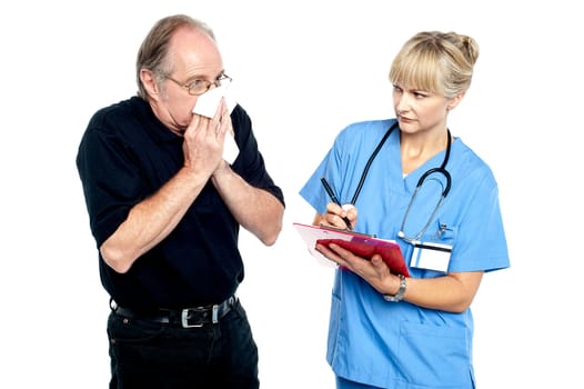 Aged male suffering from cold, sneezing. Female doctor looking at him.