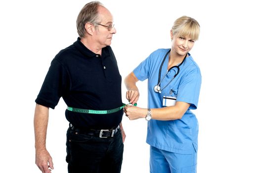 Pretty female doctor measuring waist of senior surprised man.