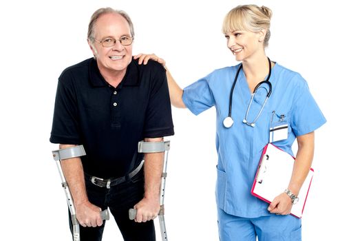 Cheerful doctor encouraging her patient to walk with crutches, smiling faces.