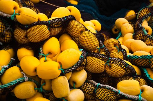 Closeup on fishing net with yellow floaters stored on fisher boat during the day