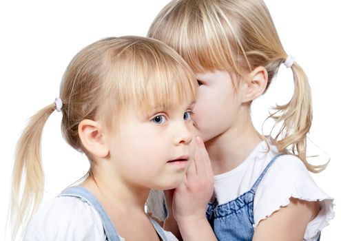 Portrait of little girl telling a secret to her friend over a white background