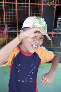 Smiling, healthy, happy, young Filipino boy wearing a hat smiles for his portrait.