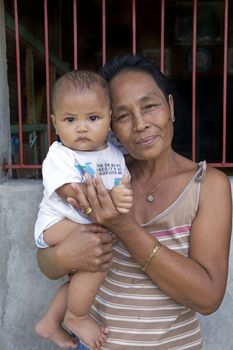 May 2012 - Cadiz City, Negros Oriental, Philippines - Pride and love expressed on the face of a Filipino grandmother holding her baby boy grandchild. Family is most important of all in the Philippines.