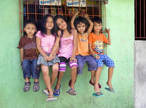 April 2012 - Cadiz City, Negros Oriental, Philippine Islands - Five beautiful young children, boys and girls, sitting on a window ledge in Cadiz City. 