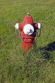Old fashioned red fire hydrant sitting in a field of grass.