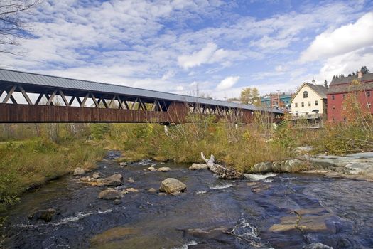 Autumn scenic of the restored wooden covered bridge over the Ammonoosuc River In Littleton, New Hampshire.