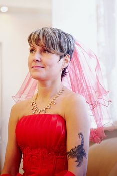Portrait of the beautiful bride in a red dress on a light background