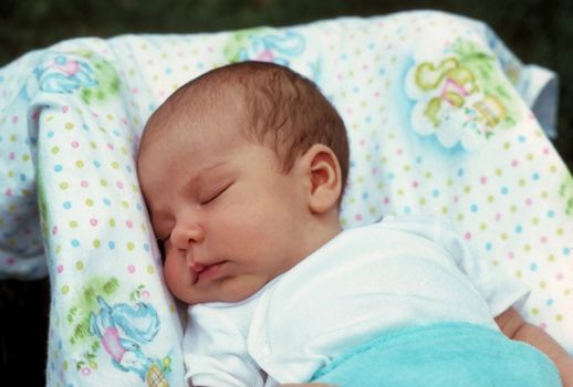 A newly born baby boy sleeping in his carrier.