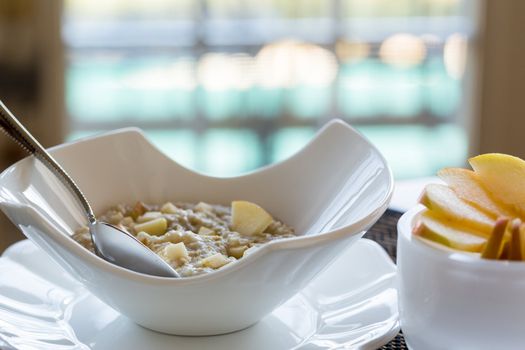 Hot oatmeal porridge or porage oats in white modern pottery bowl on breakfast table