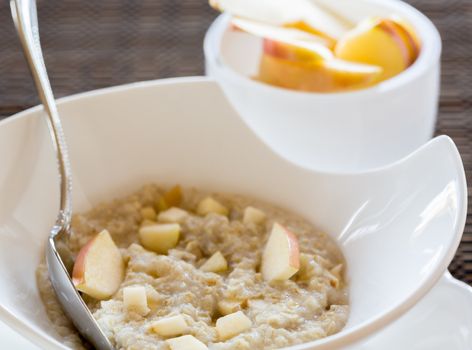 Hot oatmeal porridge or porage oats in white modern pottery bowl on breakfast table