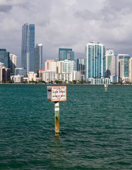 Miami cityscape skyline from Rickenbacker causeway on cloudy morning with Manatee zone slow speed sign