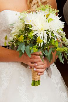 A beautiful bride holds her wedding bouquet before her ceremony with a stylish wedding photography abstract feel.