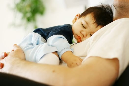 Cute biracial baby boy asleep on father's chest