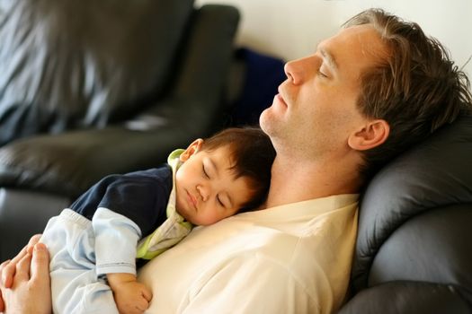 Baby boy asleep on his father's chest