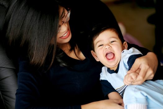 Asian mother laughing with her baby on lap