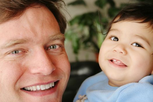 Father and biracial infant son smiling together
