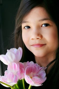 Beautiful little girl with pink tulips by face