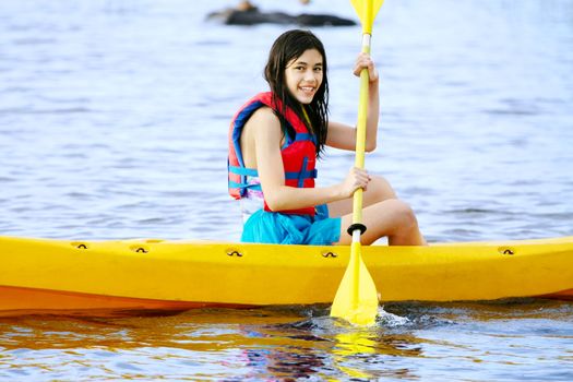 Biracial Teen girl in yellow kayak on lake
