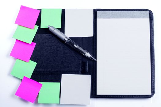 Black planner with sticky notes and pen